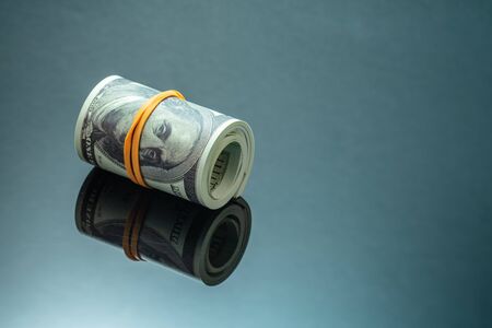 Roll of money, american dollars 100 bills on black mirror backgroundの写真素材