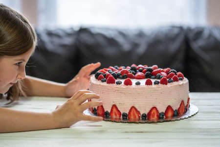 Little girl birthday cake.Home made cake with berries. Cake with Strawberry, blackberry, blueberry, and raspberry on a tableの写真素材