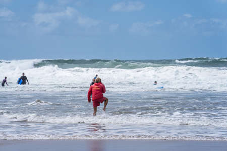 Bude, Cornwall UK July 6 2020. Lifeguard runs to sea to provide first aid to sinking surferのeditorial素材