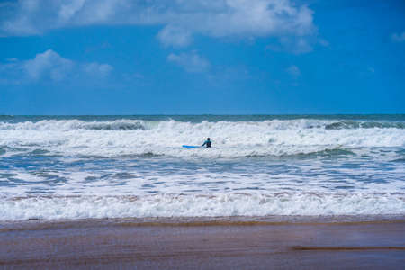Lonely surfer in a stormy sea on a board riding a wave.Bude, Cornwall UK July 6 2020のeditorial素材