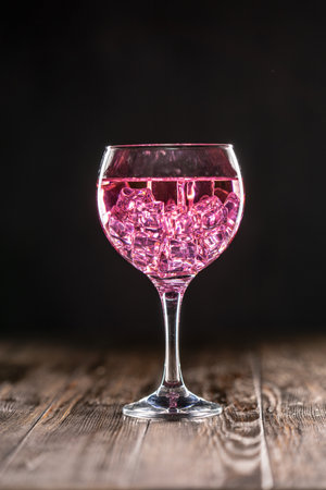 A glass with a pink cocktail filled with ice on dark backgroundの写真素材