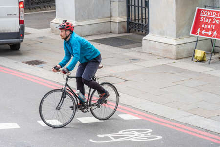A man on a bicycle crosses the street at a pedestrian crossing against a background sign keep the...