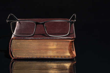 An old book with glasses lying on itの写真素材
