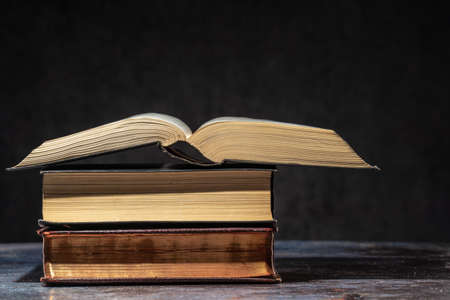 A stack of old books lying on a table on a dark backgroundの写真素材