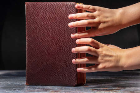 The childs hands stretching to the old book. The concept of thirst for knowledge