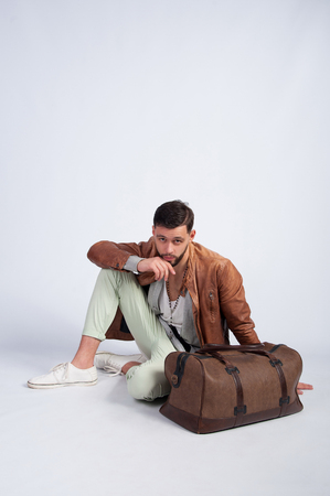 The guy sitting on the floor with a travel bagの写真素材