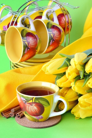 Tea cups and yellow tulips on green backgroundの写真素材