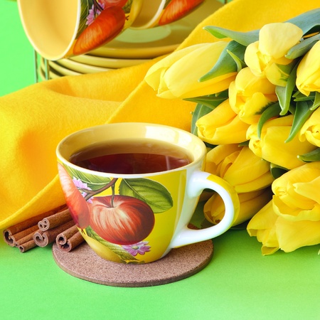 Tea cups and yellow tulips on green backgroundの写真素材