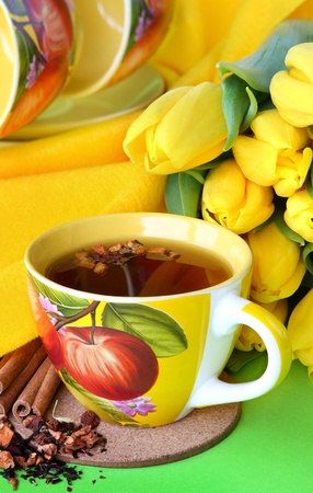 Tea cups and yellow tulips on green backgroundの写真素材
