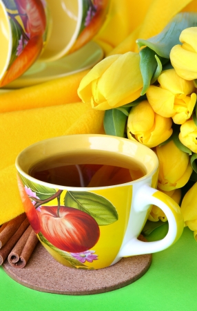 Tea cups and yellow tulips on green backgroundの写真素材