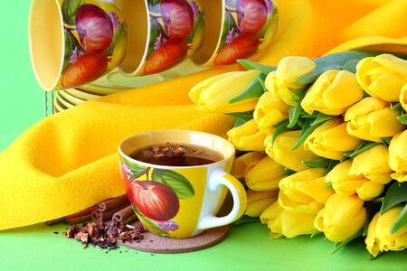 Tea cups and yellow tulips on green backgroundの写真素材