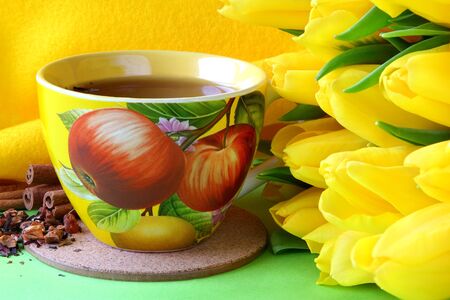 Tea cups and yellow tulips on green backgroundの写真素材