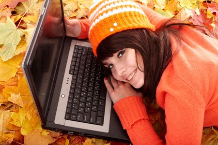 Girl in autumn orange leaves with laptop. Fall sale. Outdoor.の写真素材