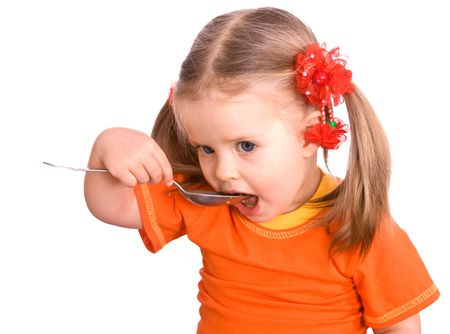 Child girl in orange shirt with spoon eat.  Isolated.の写真素材