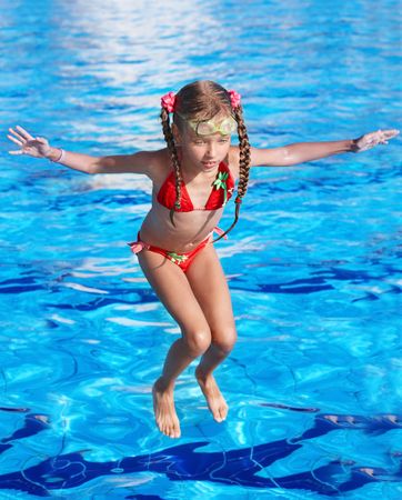 Girl with protective goggles and red swimsuit jump in swimming pool.の写真素材