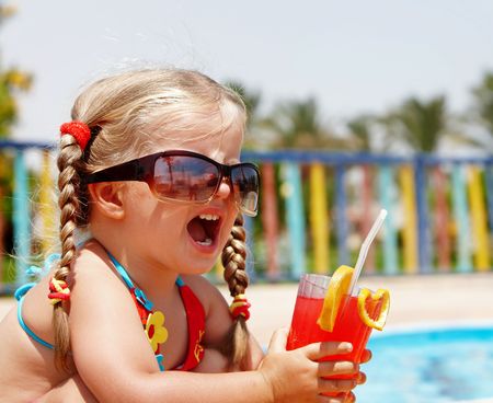Child girl in sunglasses and red bikini drink orange juice.の写真素材