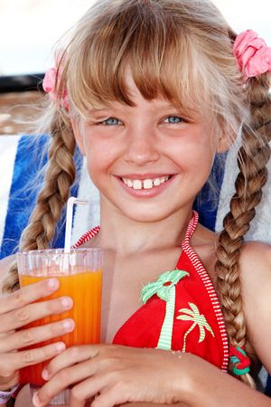 Child girl in sunglasses and red bikini drink orange juice.の写真素材
