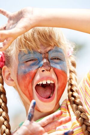 Child girl with paint on face and hand. Make up.の写真素材