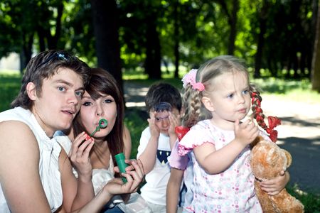 Happy family in park with soap bubbles.の写真素材
