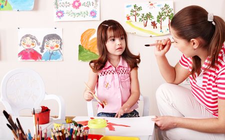 Child with teacher draw paints in play room. Preschool.の写真素材