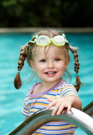 Child in protective goggles leaves pool. Outdoor.の写真素材