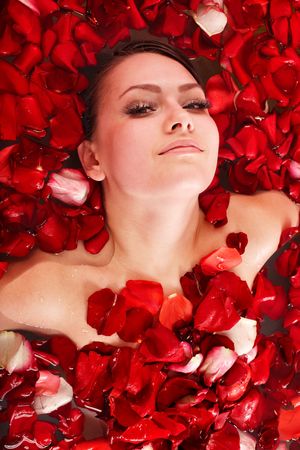 Beautiful girl in pool with rose petal. Body care.の写真素材