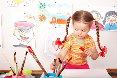 Little girl with picture and brush in playroom.の写真素材