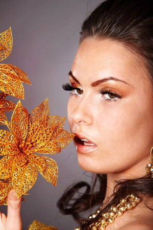 Beautiful young woman with gold flower on grey background.の写真素材
