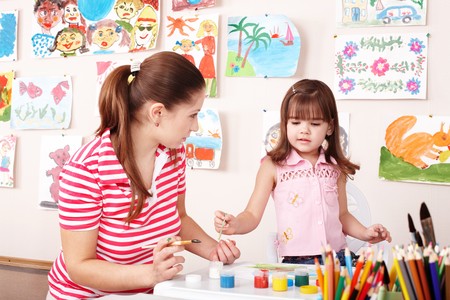 Child with teacher draw paints in play room. Preschool.の写真素材