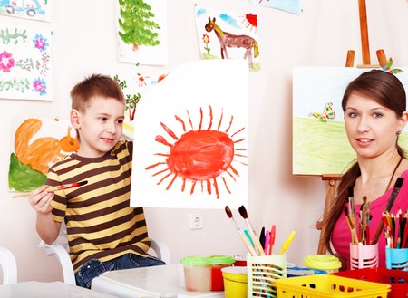 Child with teacher draw paint in play room. Preschool.の写真素材