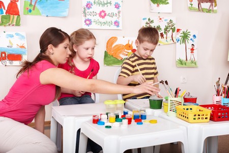 Children painting with teacher in art class. Child care.の写真素材