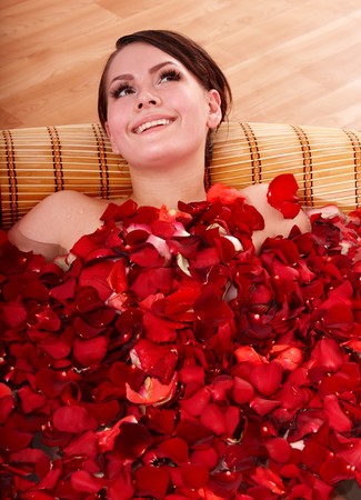 Beautiful young woman in rose petal swim water. Beauty spa.の写真素材