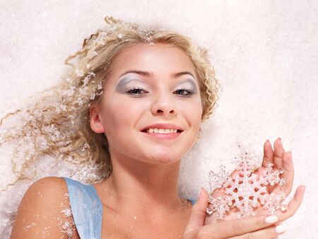 Young beautiful woman holding snowflake. Fashion studio shot.の写真素材