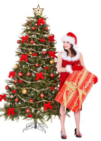 Girl in santa hat holding gift box by christmas tree.  Isolated.の写真素材