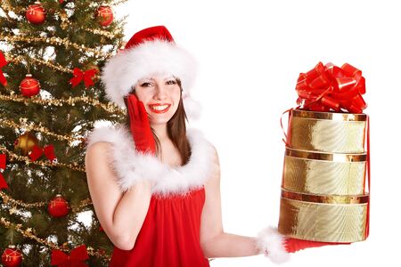 Girl in santa hat holding stack gift box near christmas tree.  Isolated.の写真素材