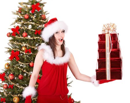 Girl in santa hat holding stack gift box near christmas tree.  Isolated.の写真素材