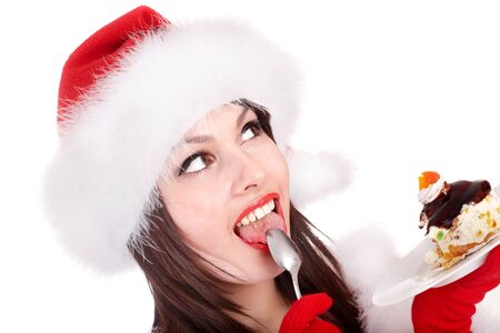 Christmas girl in red santa hat eating cake on plate. Isolated.の写真素材
