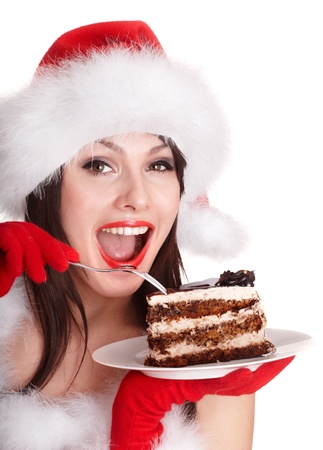 Christmas girl in red santa hat eating cake on plate. Isolated.の写真素材