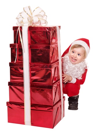 Little girl in santa hat  by stack gift box. Isolated.の写真素材