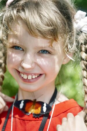 Happy child with butterfly on neck.Nature.の写真素材