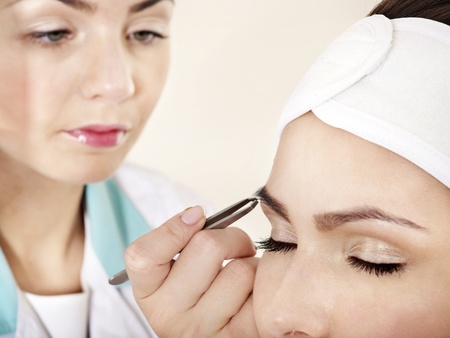 Tweezing eyebrow by beautician. Isolated.の写真素材