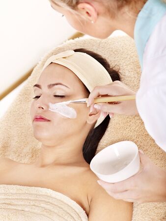 Beautician applying  facial mask by young woman.の写真素材