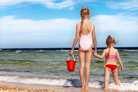 Children holding hands walking on the beach. Rear view.の写真素材