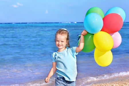 little girl playing with balloons at the beach.の写真素材