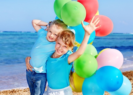 little girl playing with balloons at the beach.の写真素材