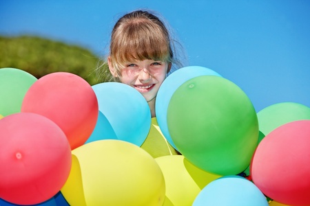 little girl playing with balloons at the beach.の写真素材