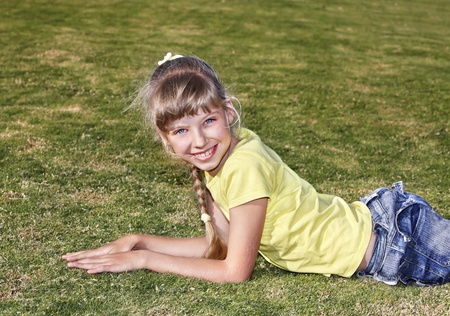 Little girl lying on green grass . Outdoor.の写真素材