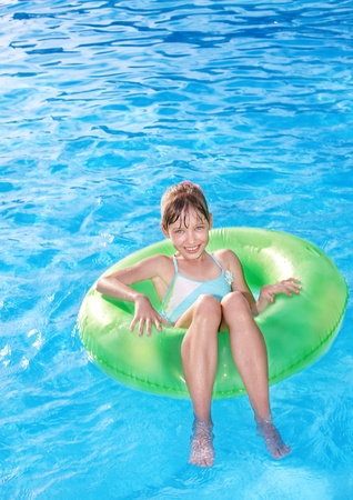 Children sitting on inflatable ring in swimming pool.の写真素材