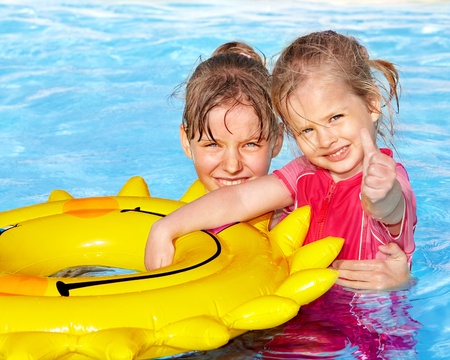 Children sitting on inflatable ring in swimming pool.の写真素材