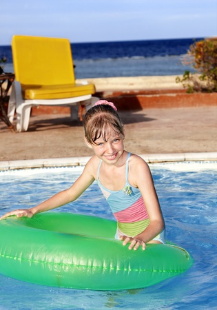 Children sitting on inflatable ring in swimming pool.の写真素材